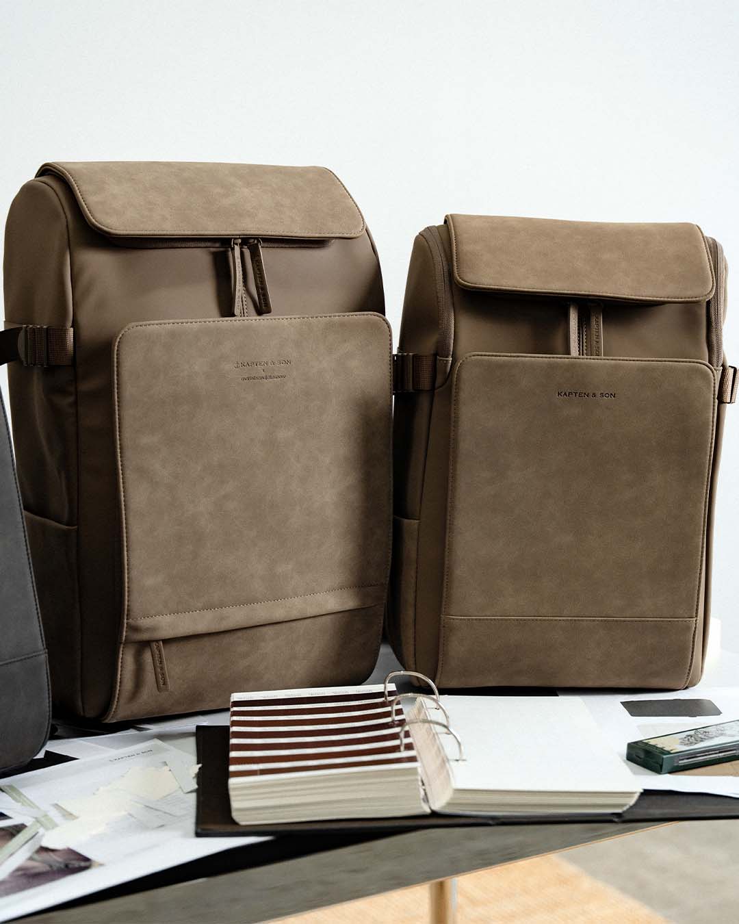 Two brown backpacks on a table with a magazine underneath.