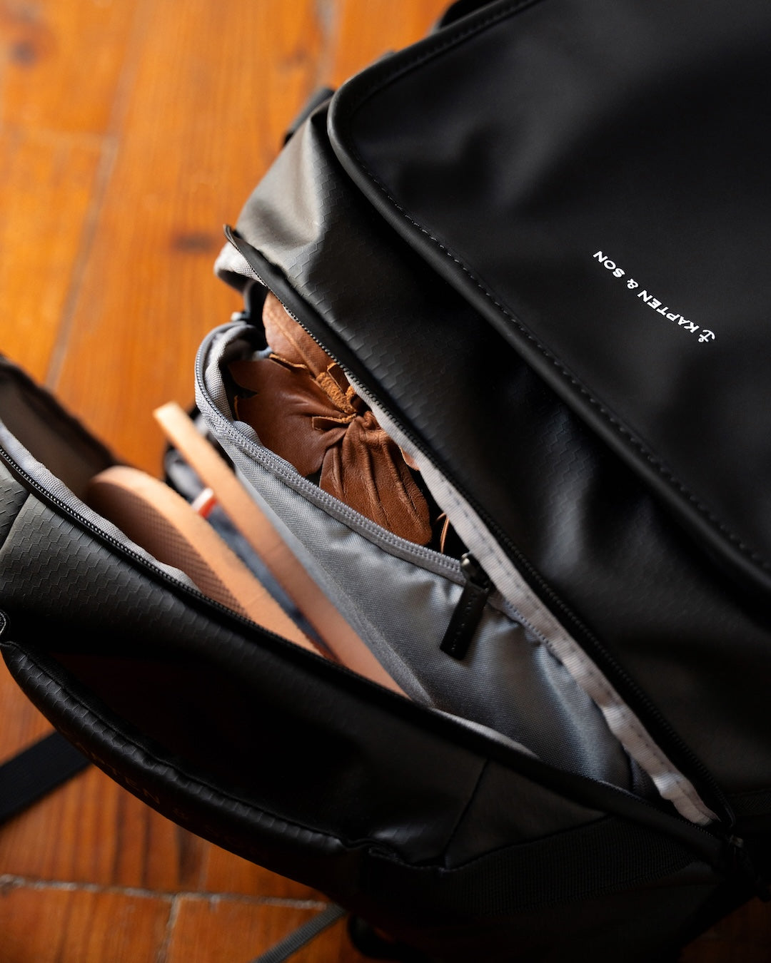 Black backpack with a brown item inside on a wooden floor
