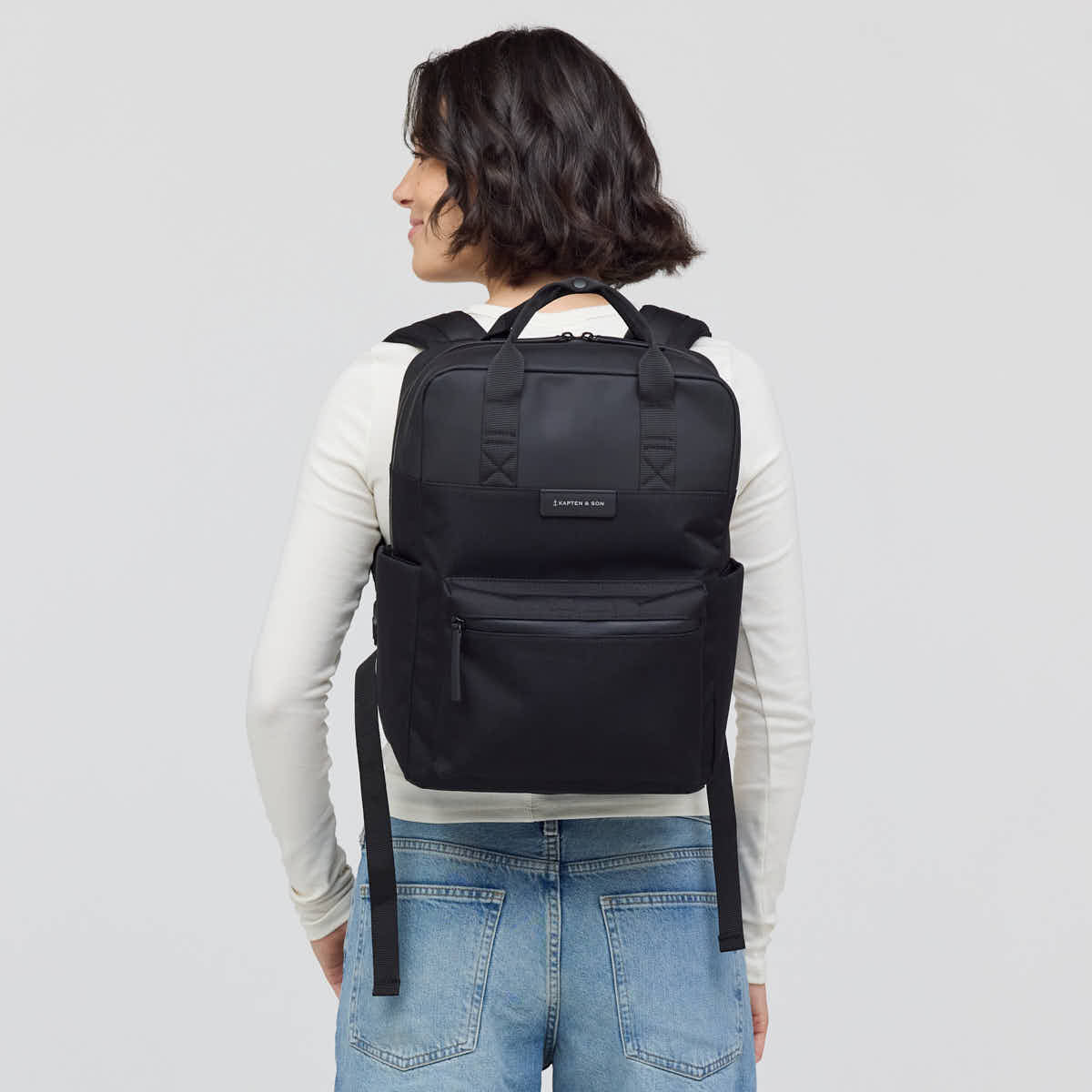 Person wearing a black backpack on a plain background