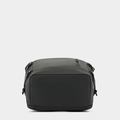 A black soft-sided backpack with a matte finish, shown from the bottom against a light gray studio background.