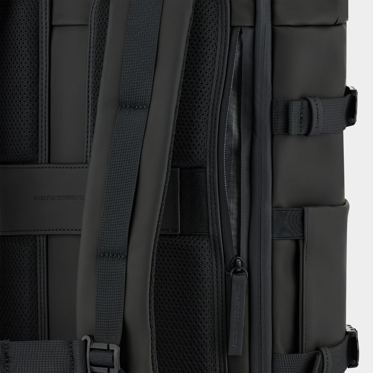 Close-up of a black backpack showing the back padding, shoulder straps, mesh ventilation panels, and side zipper compartments.