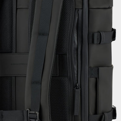 Close-up of a black backpack showing the back padding, shoulder straps, mesh ventilation panels, and side zipper compartments.