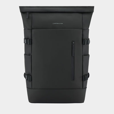 A black  backpack with a vertical zippered pocket on the front, side compression straps, and a small white 'KAPTEN & SON' logo, shown against a light gray background.