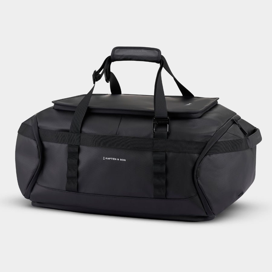 Black duffel bag with straps on a gray background