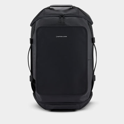 A black Kapten & Son Duffle backpack shown from the front on a light gray background.