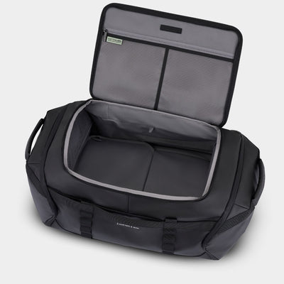 Black duffel bag with open top on a light grey  background