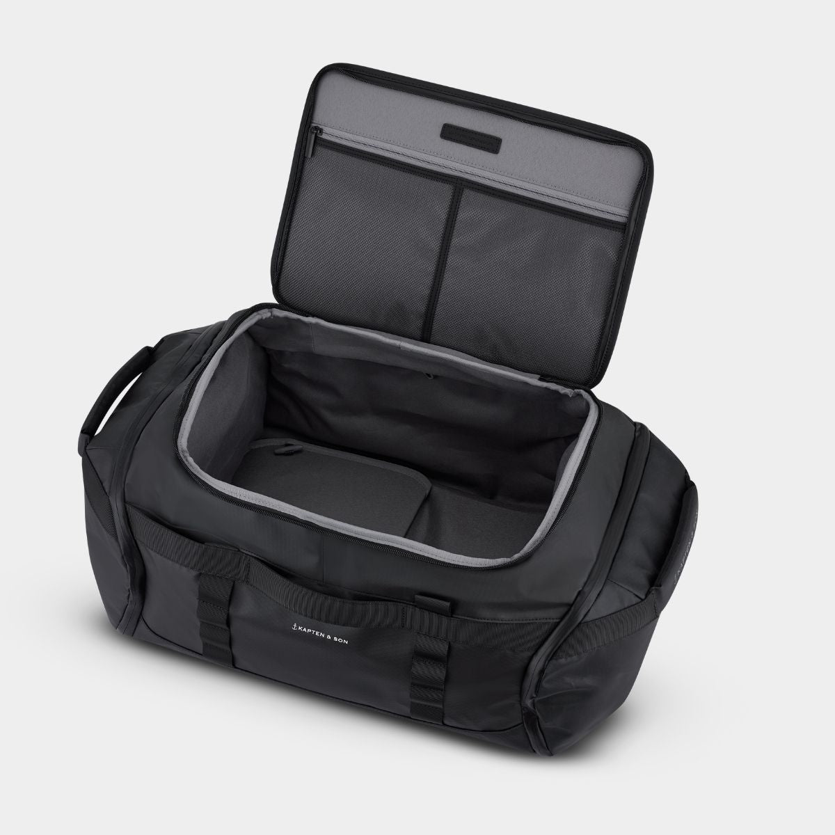 A black duffel bag with its lid open, showing a spacious interior with gray lining and organizational pockets, photographed on a light gray background.