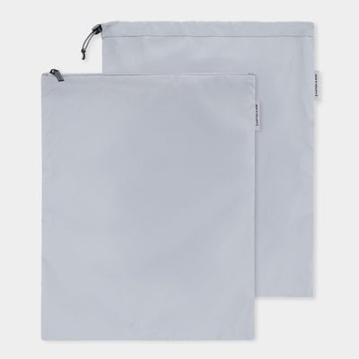 Two light gray drawstring storage bags one with zipper closure and one with draw string, shown overlapping on a clean white background.