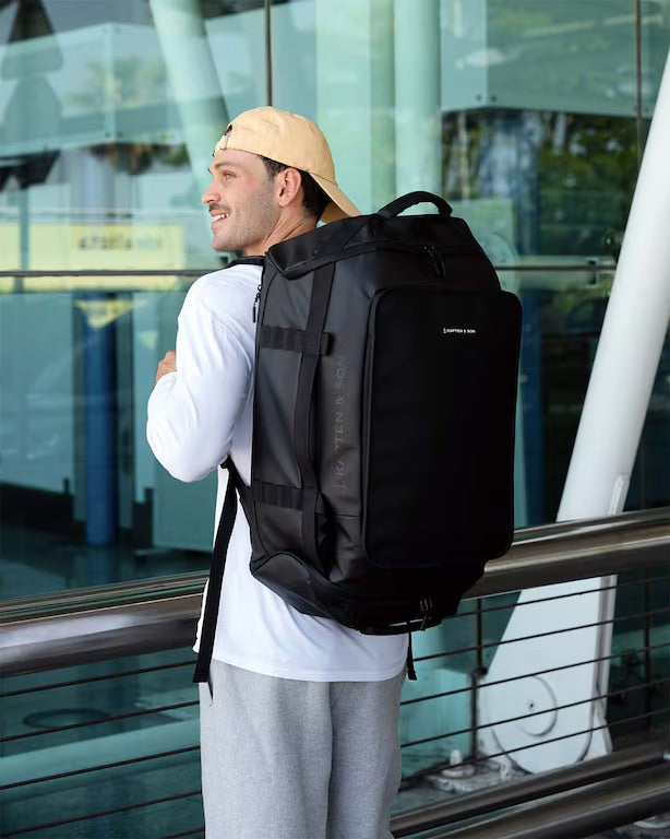 Man wearing a black backpack in front of a glass building