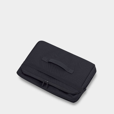 Folded black pouch with top handle and zipper closure held together with an elastic strap 