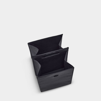 A black fabric organizer box with a fold-out design, shown open on a light gray background.
