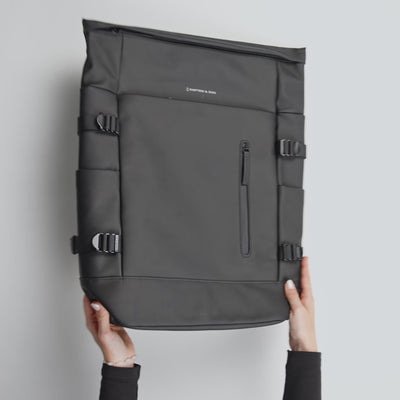 Video packing a black backpack that fully opens from the back, packed with clothing, water bottle, headphones and lip gloss