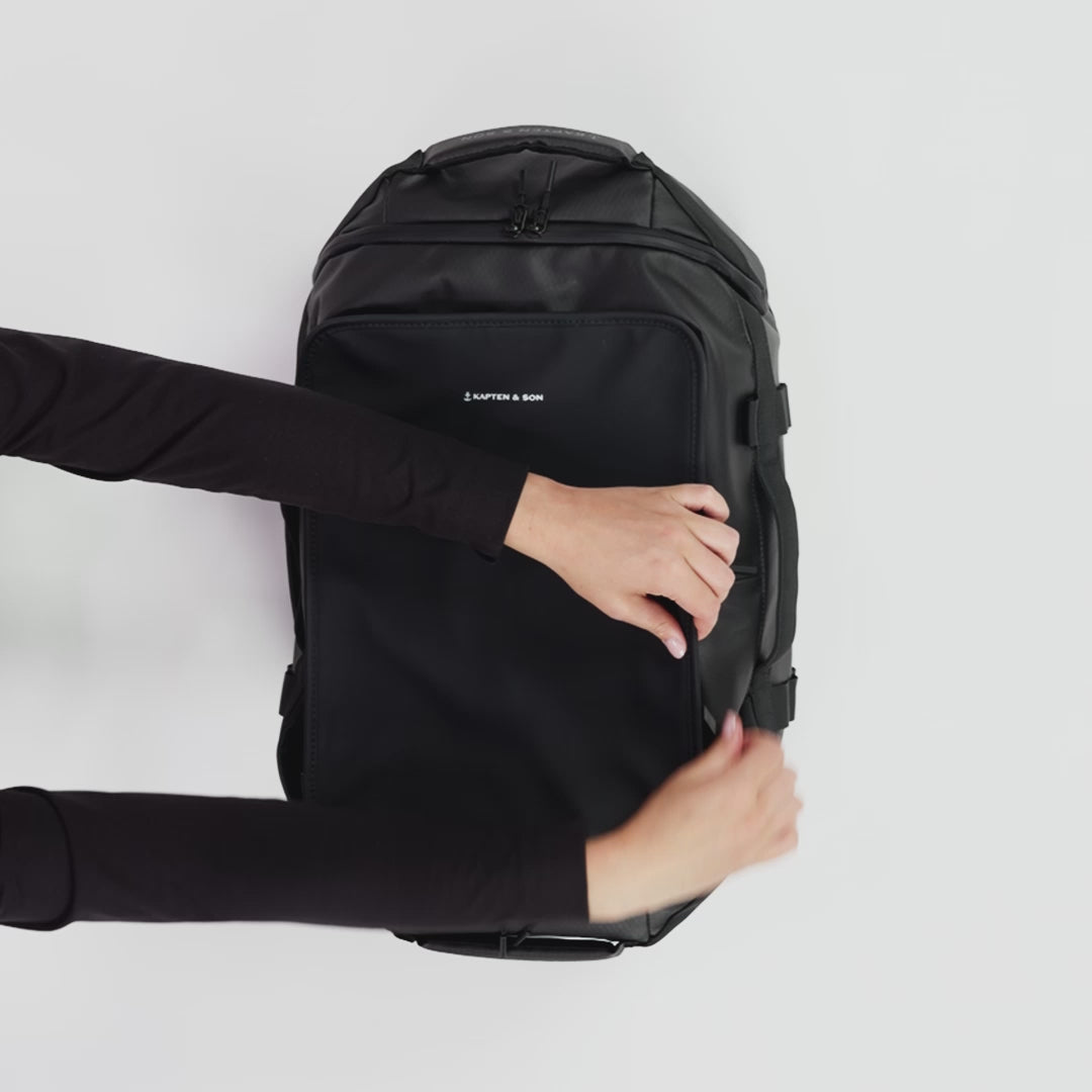 A packing video of a medium black backpack showing all inside zipper compartments and storage pockets. Packing with things to show the capacity and ability to carry as a duffle bag or a backpack.